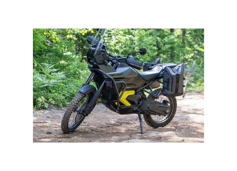 Can-Am Origin adventure motorcycle with black side guards parked on forest trail