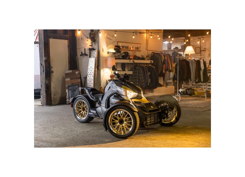 Can-Am Ryker three-wheeler with Circuit rear wheel in Liquid Gold, side view in vintage garage