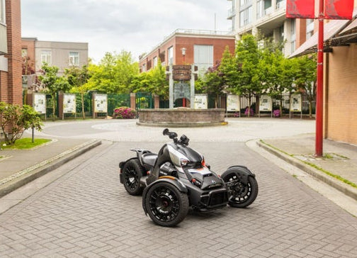 Can-Am Ryker Rally three-wheeler parked on brick plaza showing rear wheel deep black finish