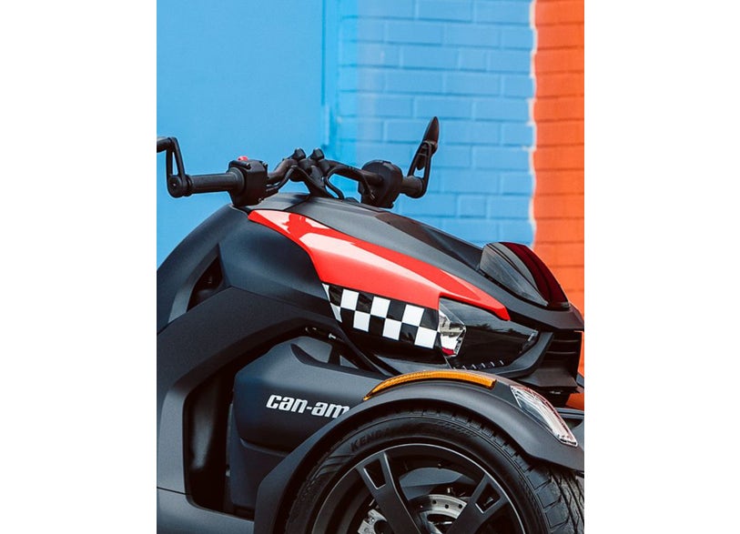 Can-Am Ryker three-wheeler front end with black cluster relocator handlebar mount, red checkered accent panel