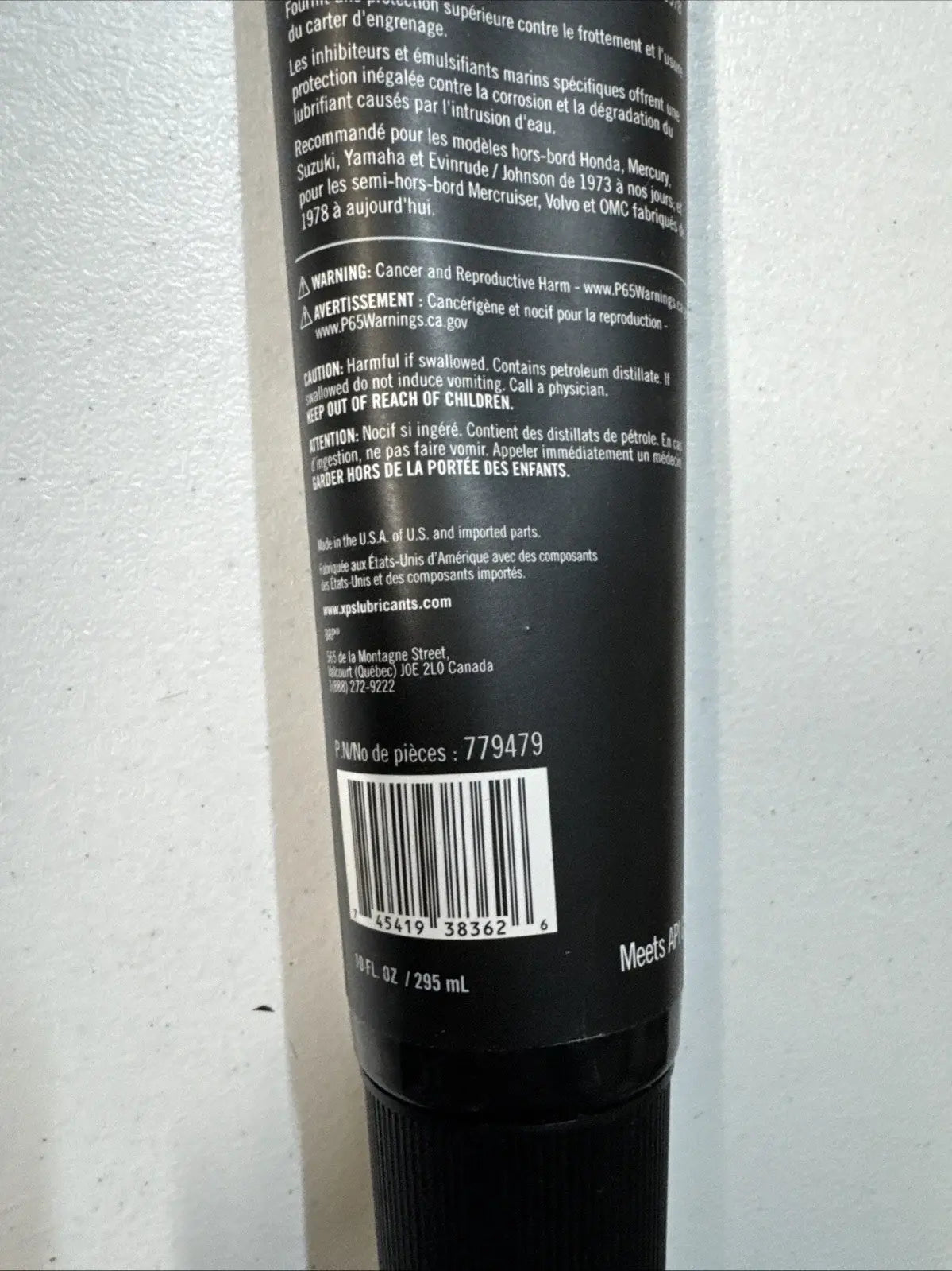 Close-up of a black cylindrical product with text and a barcode on a light gray background