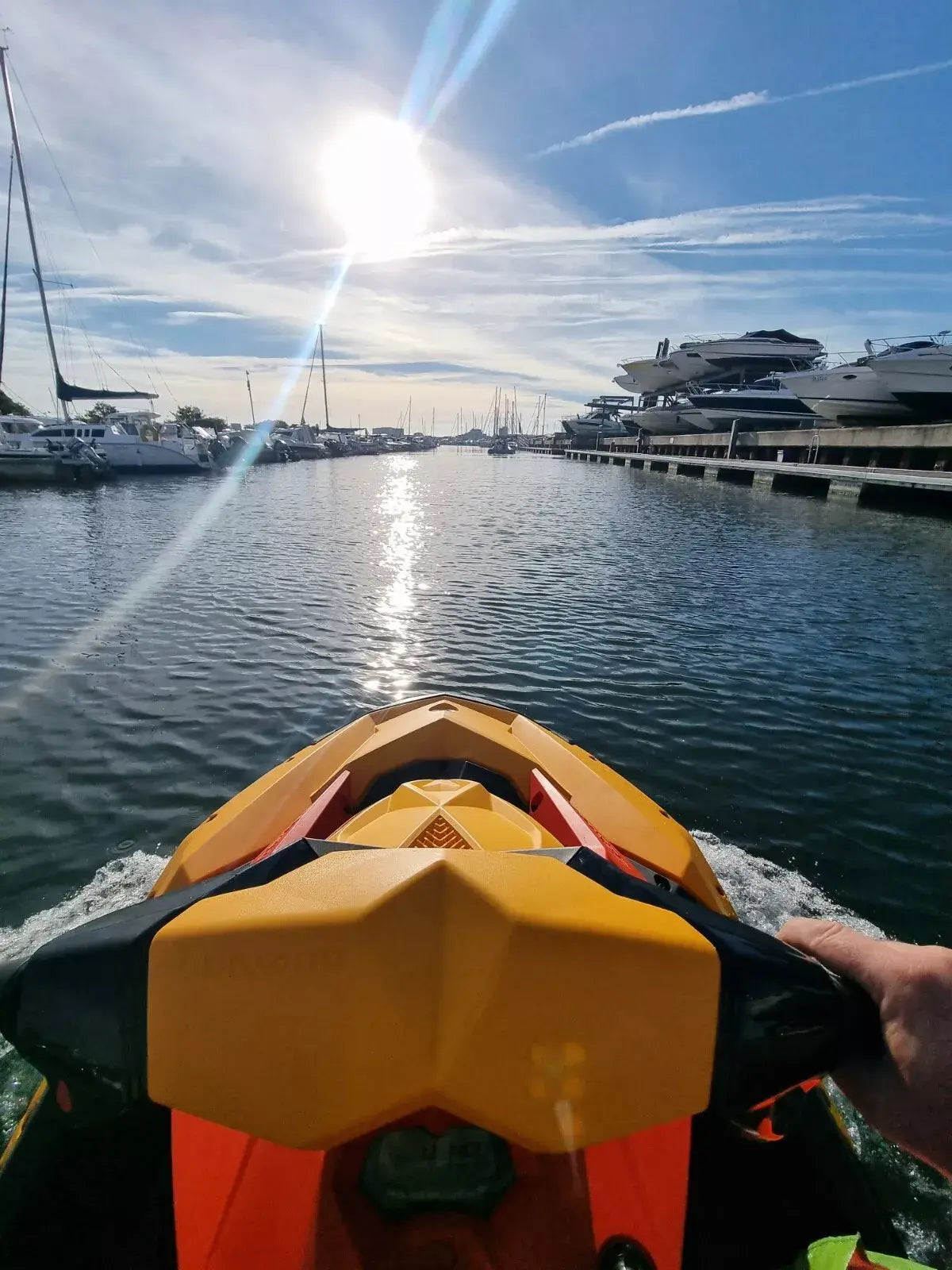 View from a Sea-Doo jet ski heading towards a marina with yachts under a sunny sky.