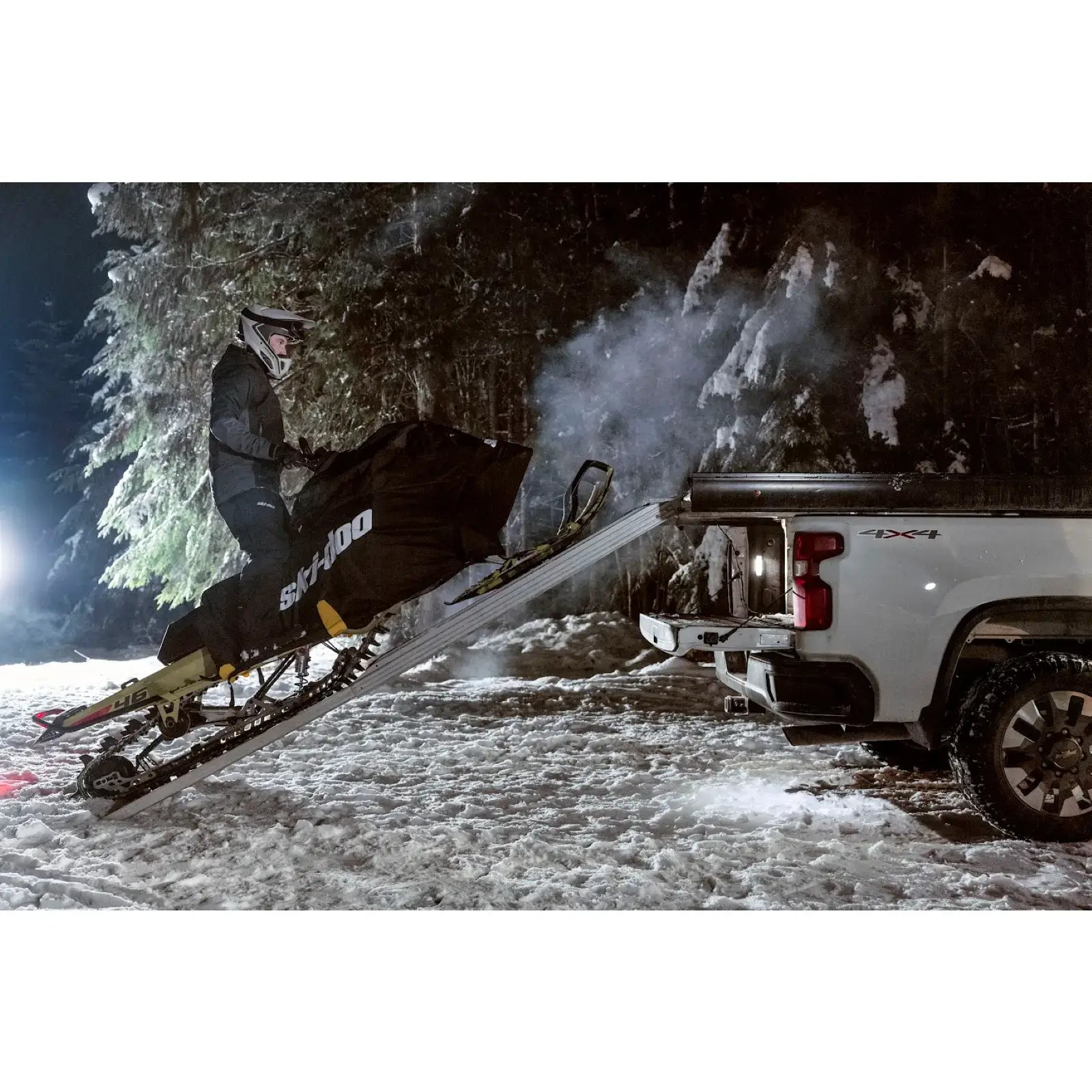 person loading ski-doo onto truck in winter with ride on cover